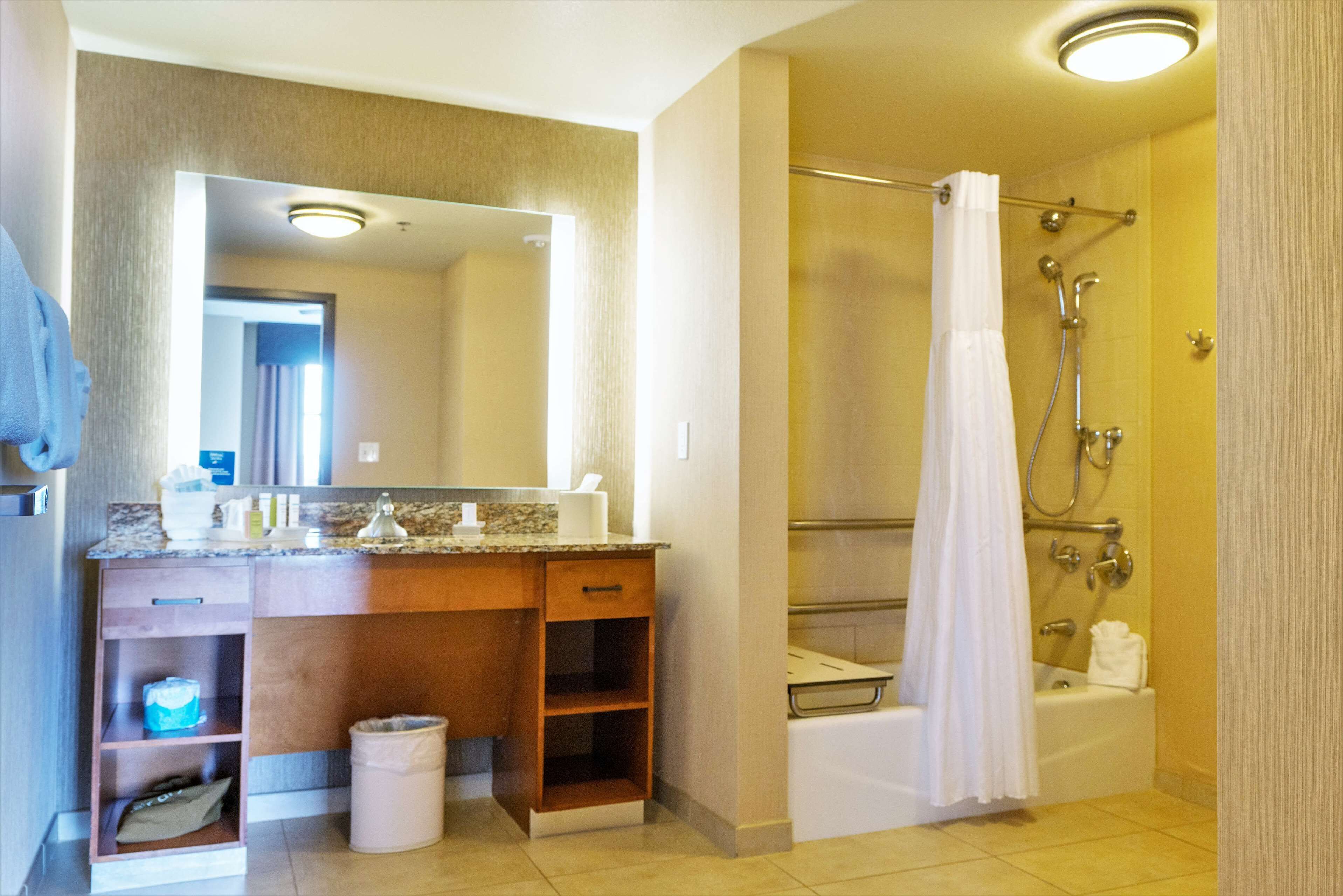A bathroom with a sink, mirror, vanity, shower, and bathtub.
