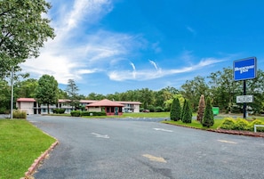 A motel with a red roof, a signboard for 'Rodeway Inn,' and a parking lot with directional arrows.