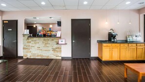 Un espace d’accueil doté d’un comptoir en pierre, d’armoires en bois et d’une machine à café.