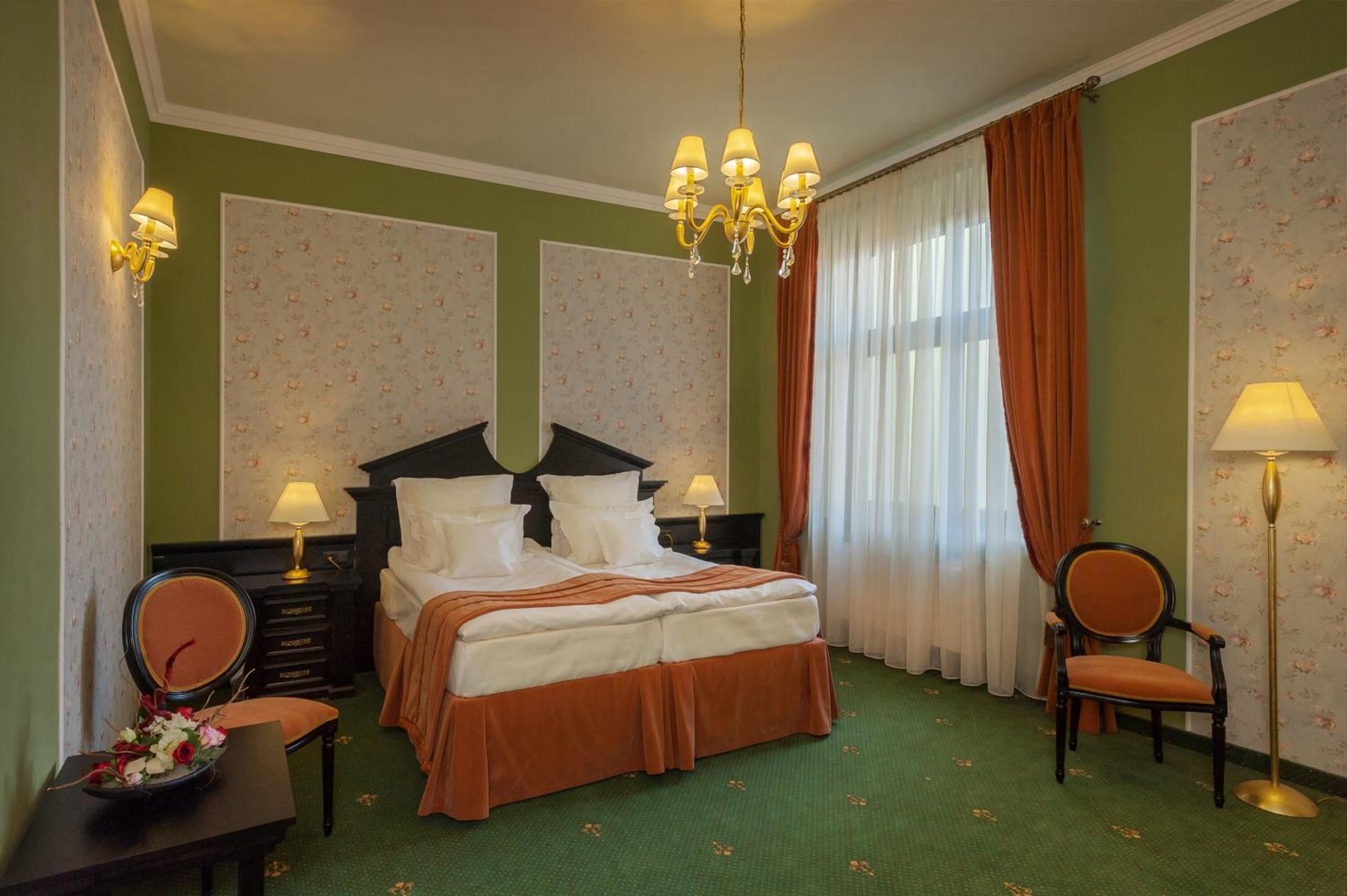 A hotel room with a large bed, two bedside tables with lamps, a chair, and a floor lamp.