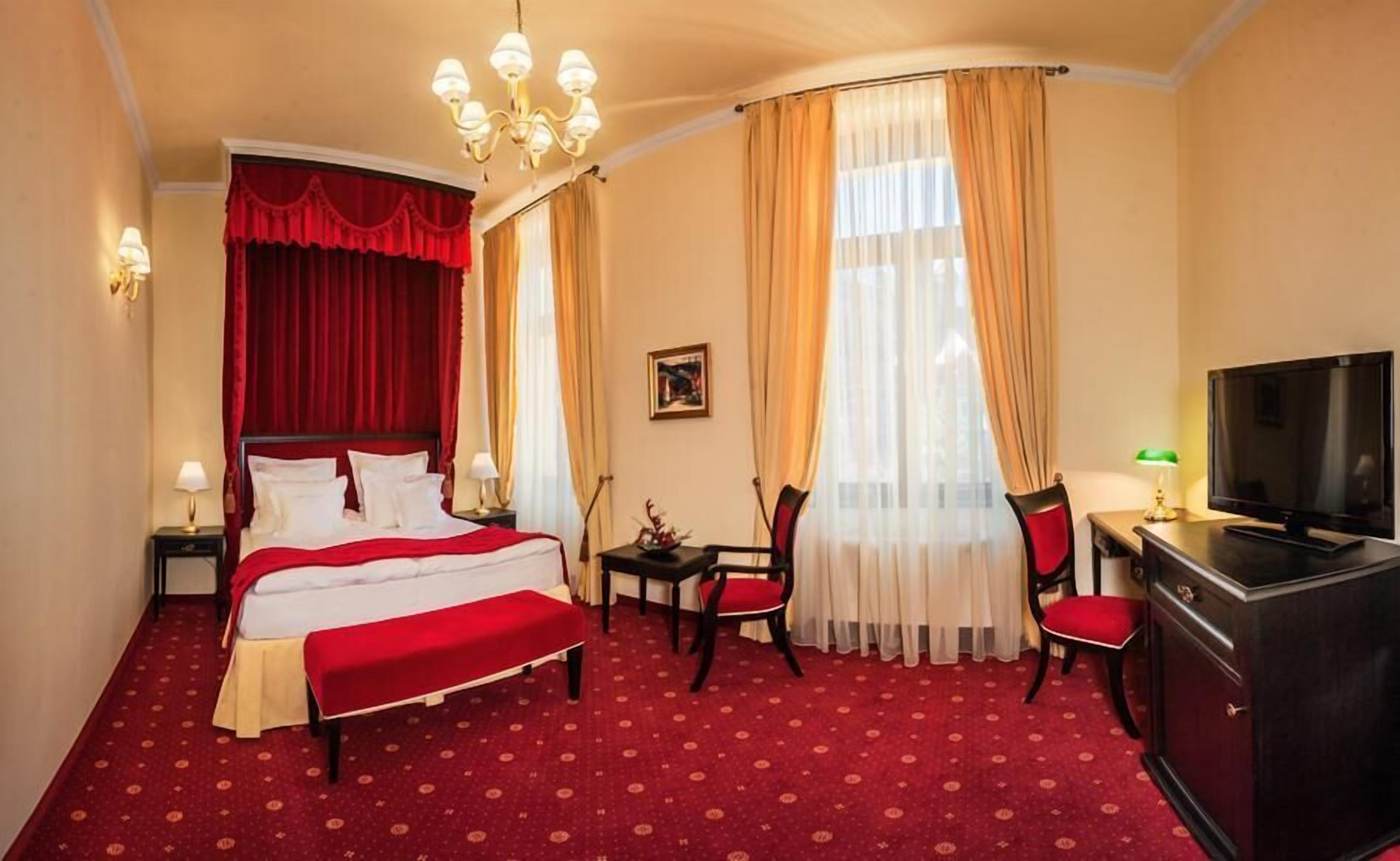 Una habitación de hotel con una cama grande, un escritorio con televisor y una silla.