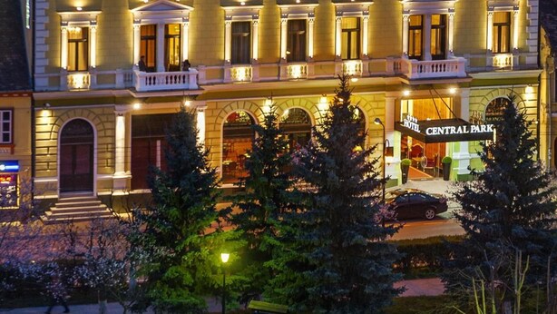Un hotel con acceso al parque central, varios balcones y un estilo arquitectónico clásico.