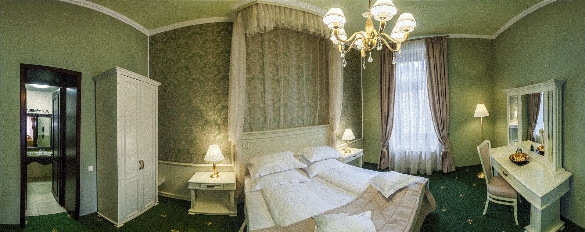 Habitación de hotel con una cama grande, una mesita de noche con lámpara, un tocador con espejo y un armario.