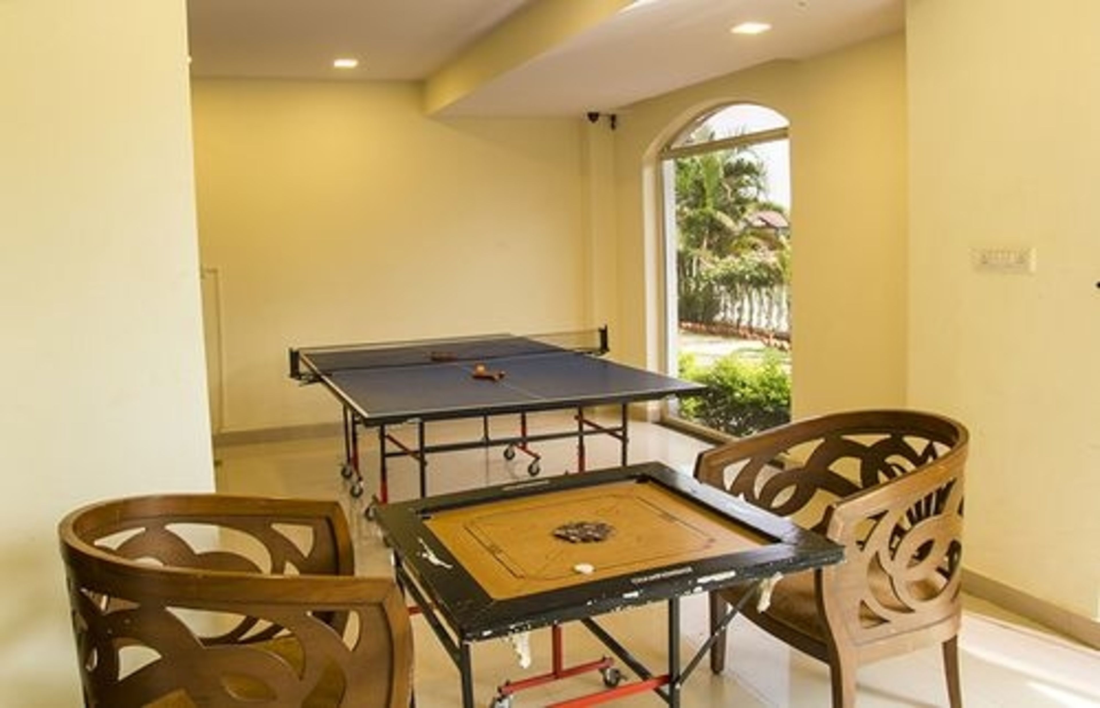 A pool table in a room with yellow walls and a view of greenery outside.