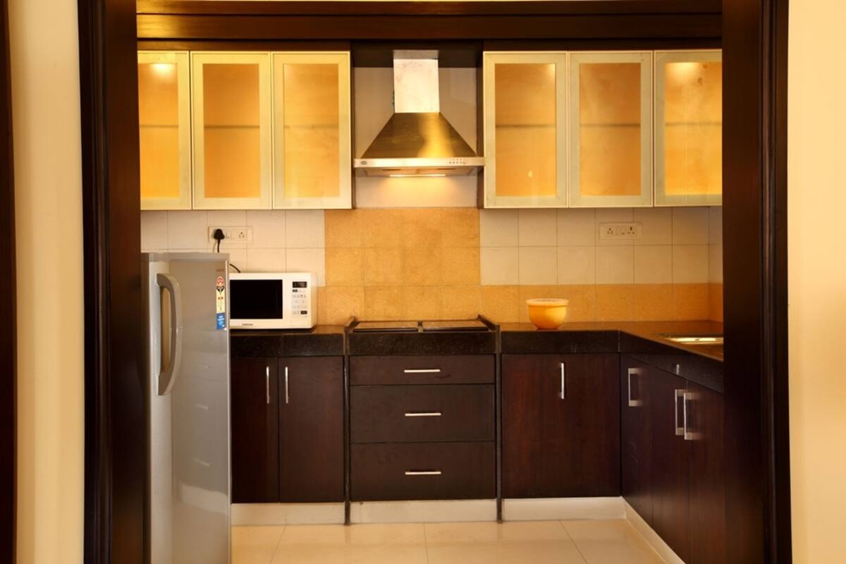 A kitchen with dark wooden cabinets, a stainless steel range hood, and a white microwave.