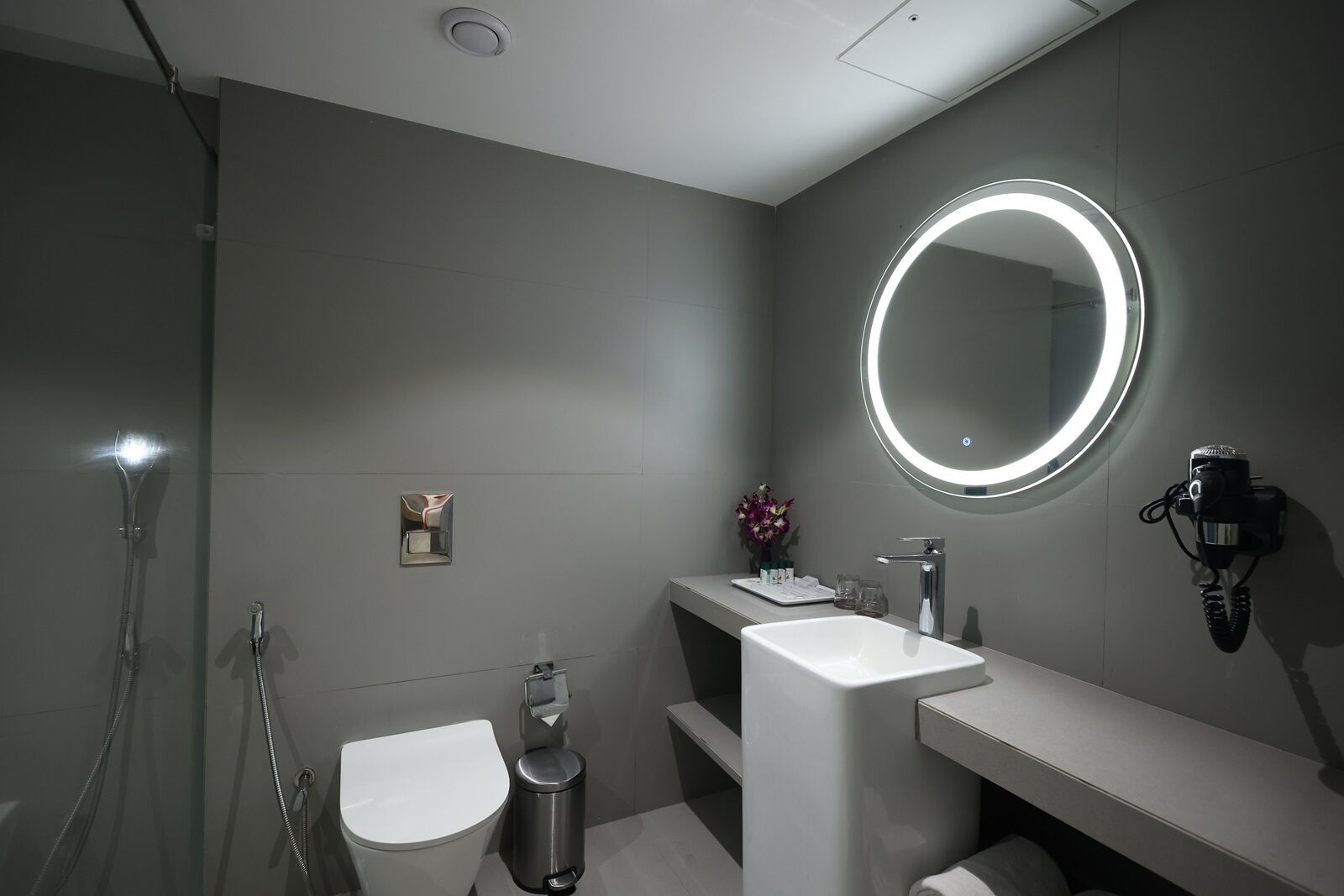 Une salle de bain moderne équipée de toilettes, d’un bidet et d’un lavabo avec un miroir.