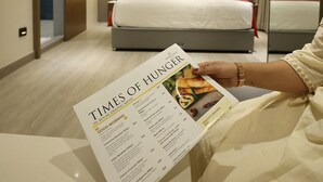 A hotel room with a bed, a nightstand, and a menu on the table. - Marigold- Newly Renovated Hotel (Rahata)