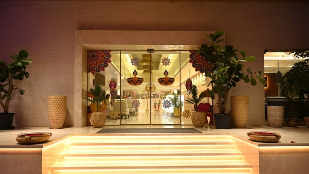 A hotel lobby with a glass entrance, decorative lamps, and potted plants. - Marigold- Newly Renovated Hotel (Rahata)