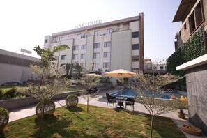 A hotel named Marigold with a swimming pool, outdoor seating, and a well-maintained garden.