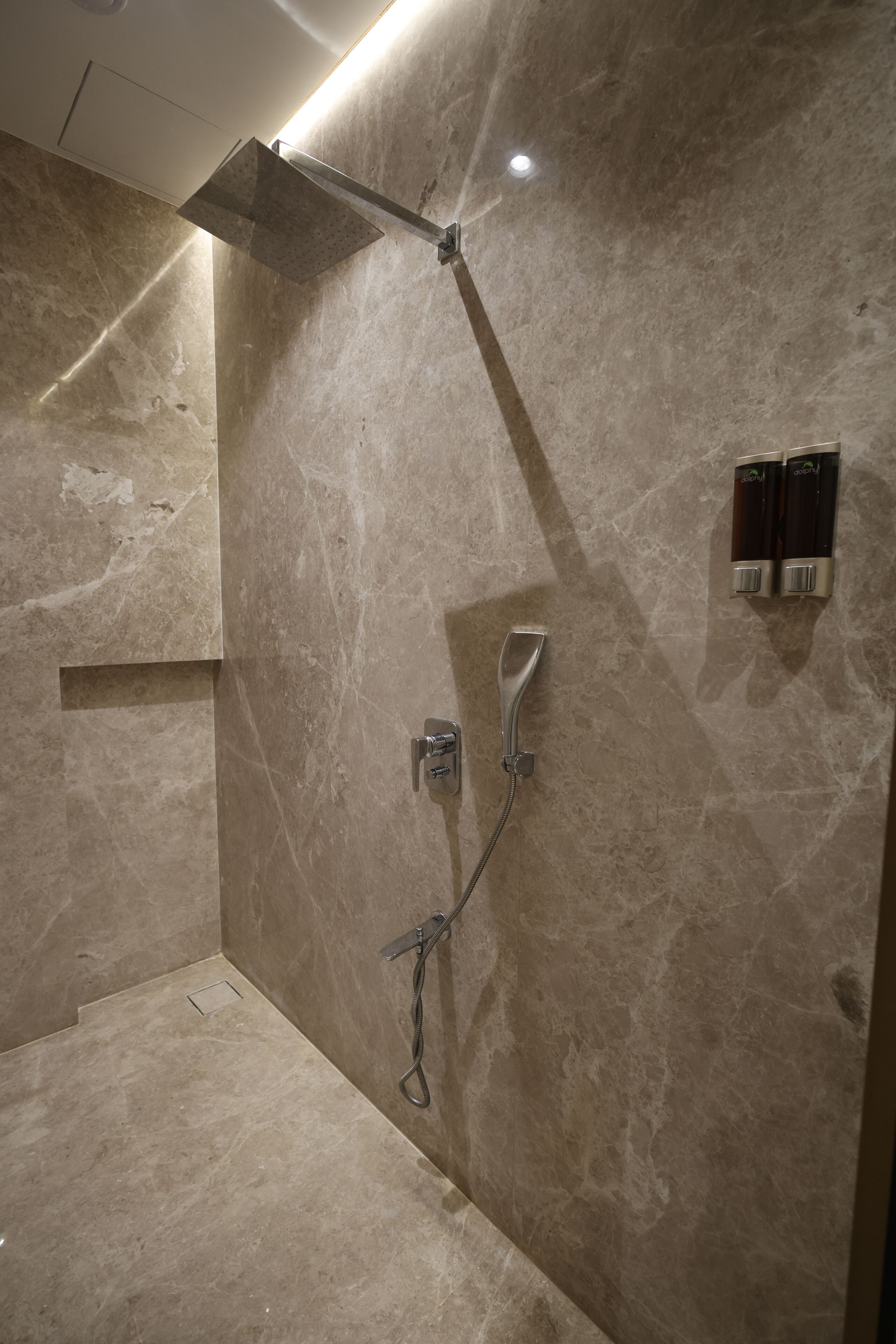Une salle de bain moderne équipée d’une douche, d’un porte-serviettes et d’un distributeur de savon.