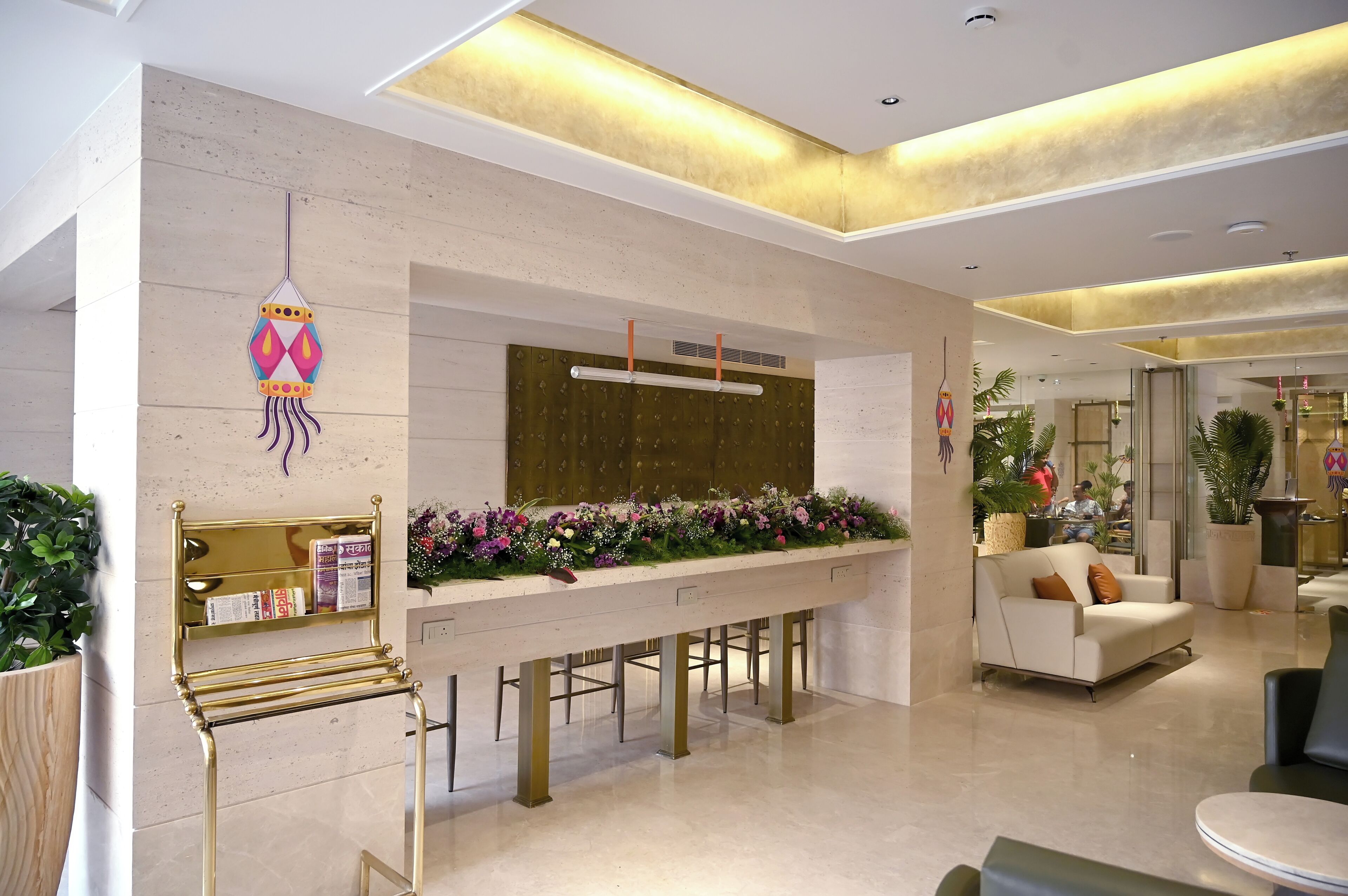 A modern lobby with a reception desk, seating area, and decorative plants.