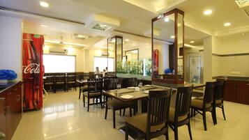 A dining area with tables and chairs, a Coca-Cola refrigerator, and a large mirror.