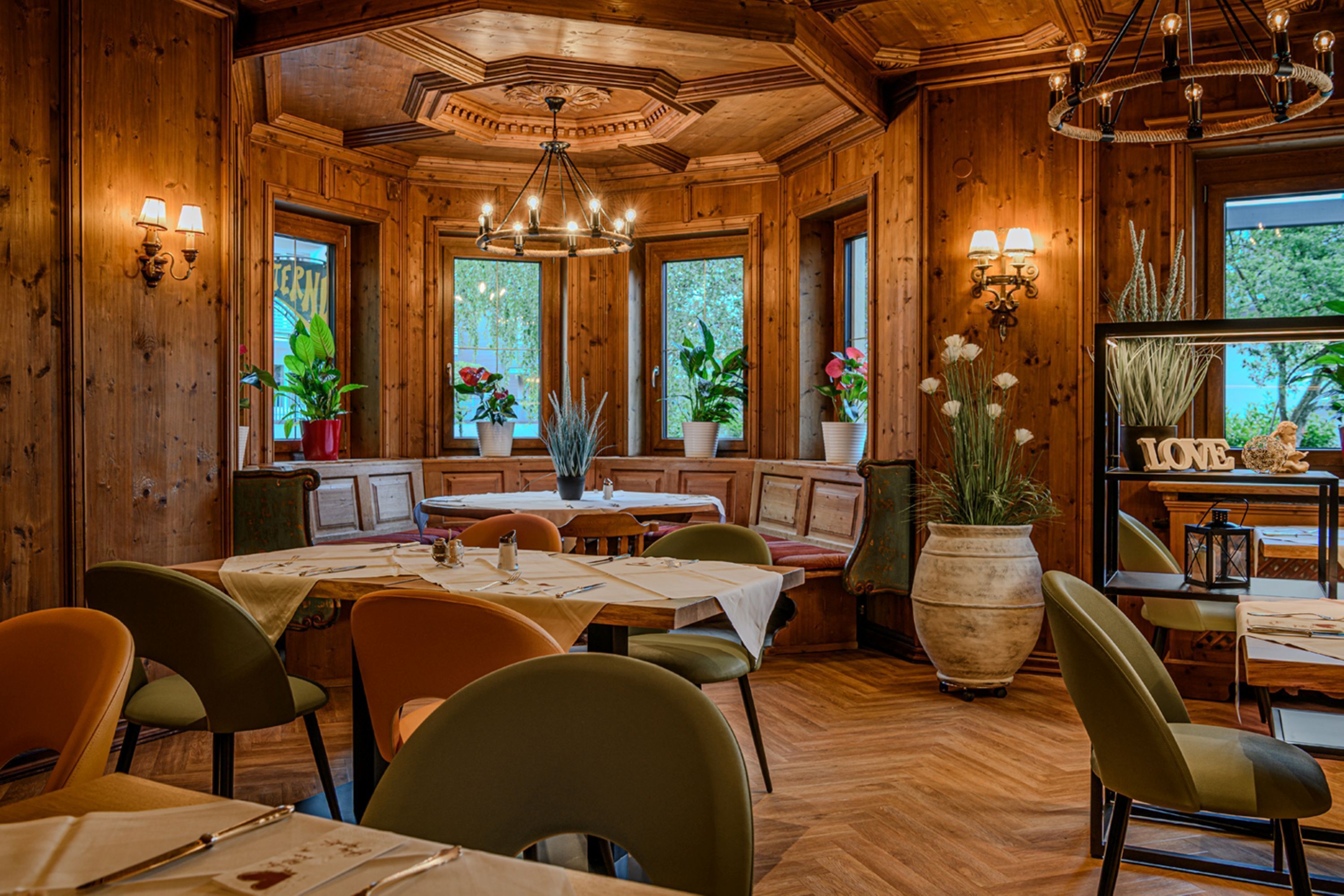 A wooden interior with tables, chairs, and a chandelier.