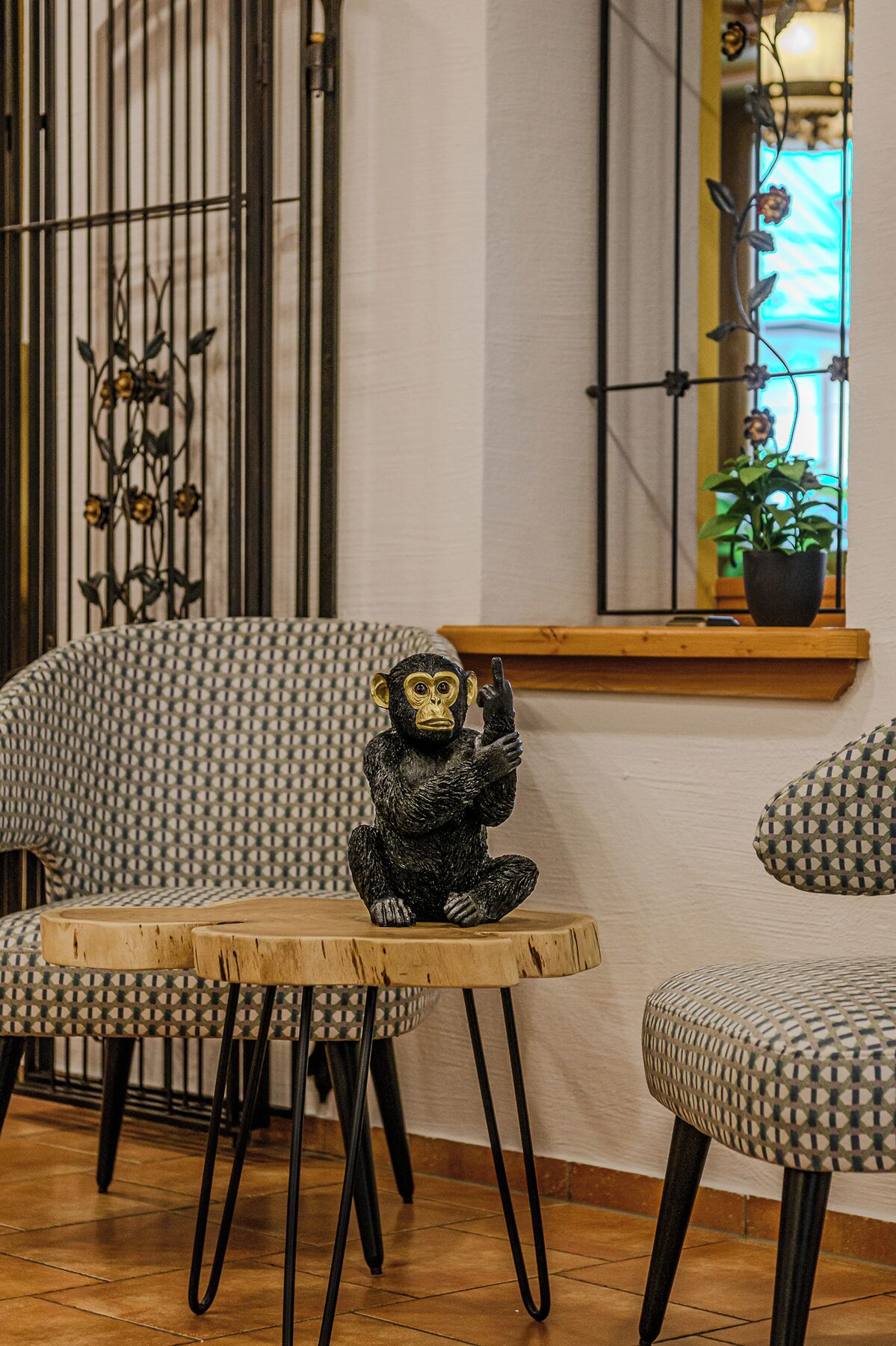 A room with patterned chairs, a small table, and a decorative monkey statue.