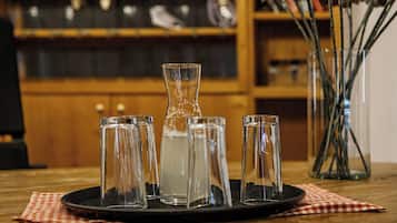 Una mesa con una jarrón, vasos, un mantel a cuadros y un fondo de madera.