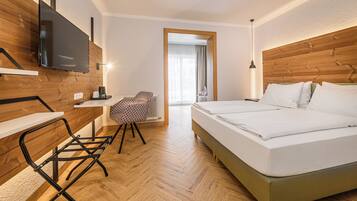 Una habitación de hotel con cama, escritorio, silla, televisión y ventana.