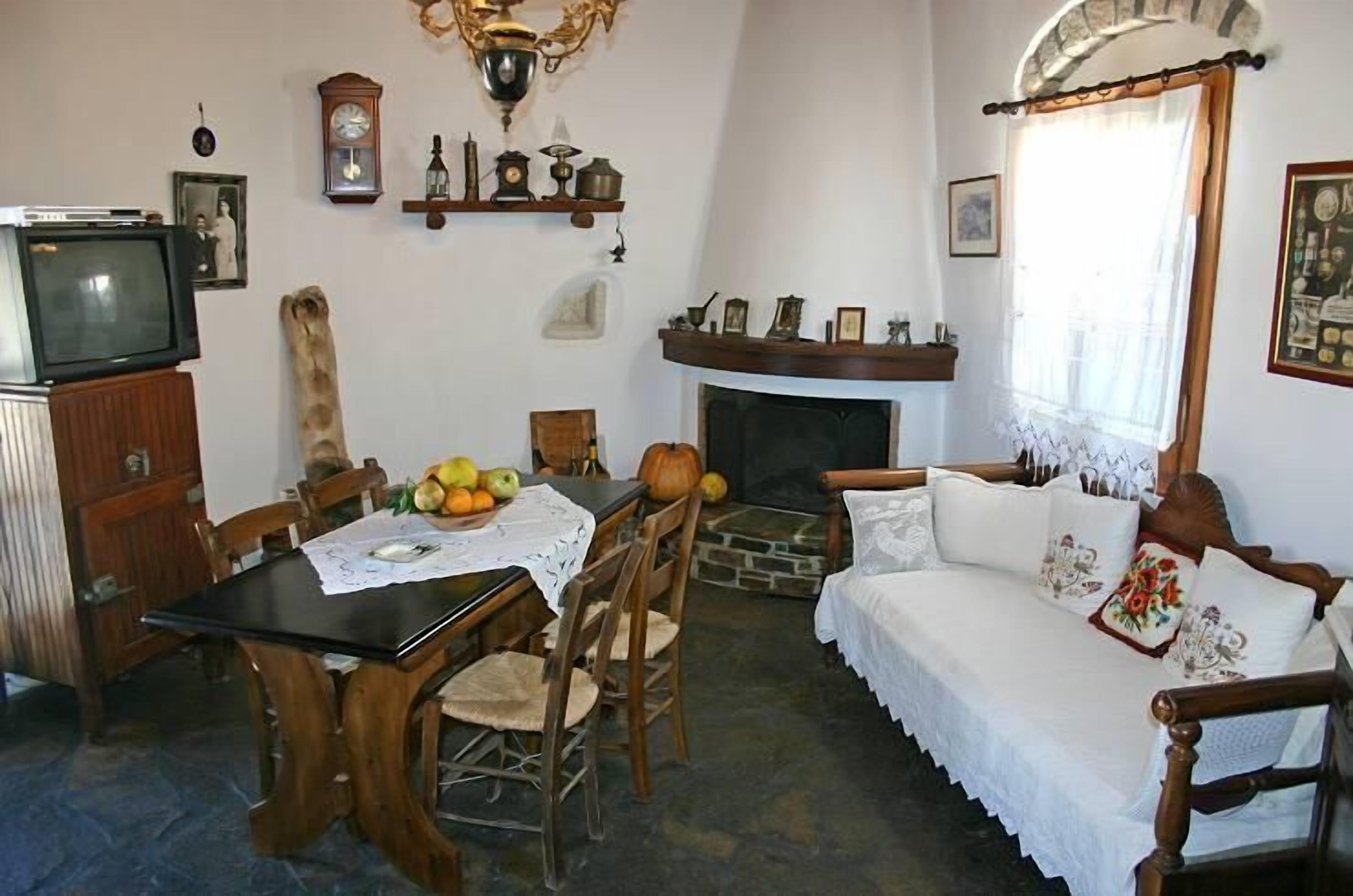 Un salón tradicional con chimenea, muebles de madera y una mesa de comedor con fruta.