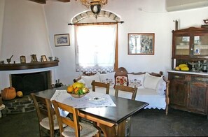 A cozy dining area with a fireplace, wooden furniture, and a fruit bowl on the table. - Hotel Naxos Filoxenia (Naxos)