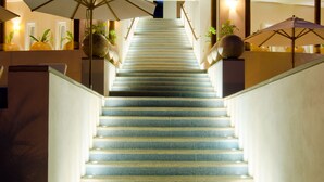 Eine Treppe mit blauen Fliesen führt zu einem Balkonbereich mit mehreren Sonnenschirmen.