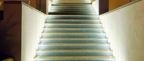 A staircase with blue-tiled steps leading up to a balcony area with multiple umbrellas.