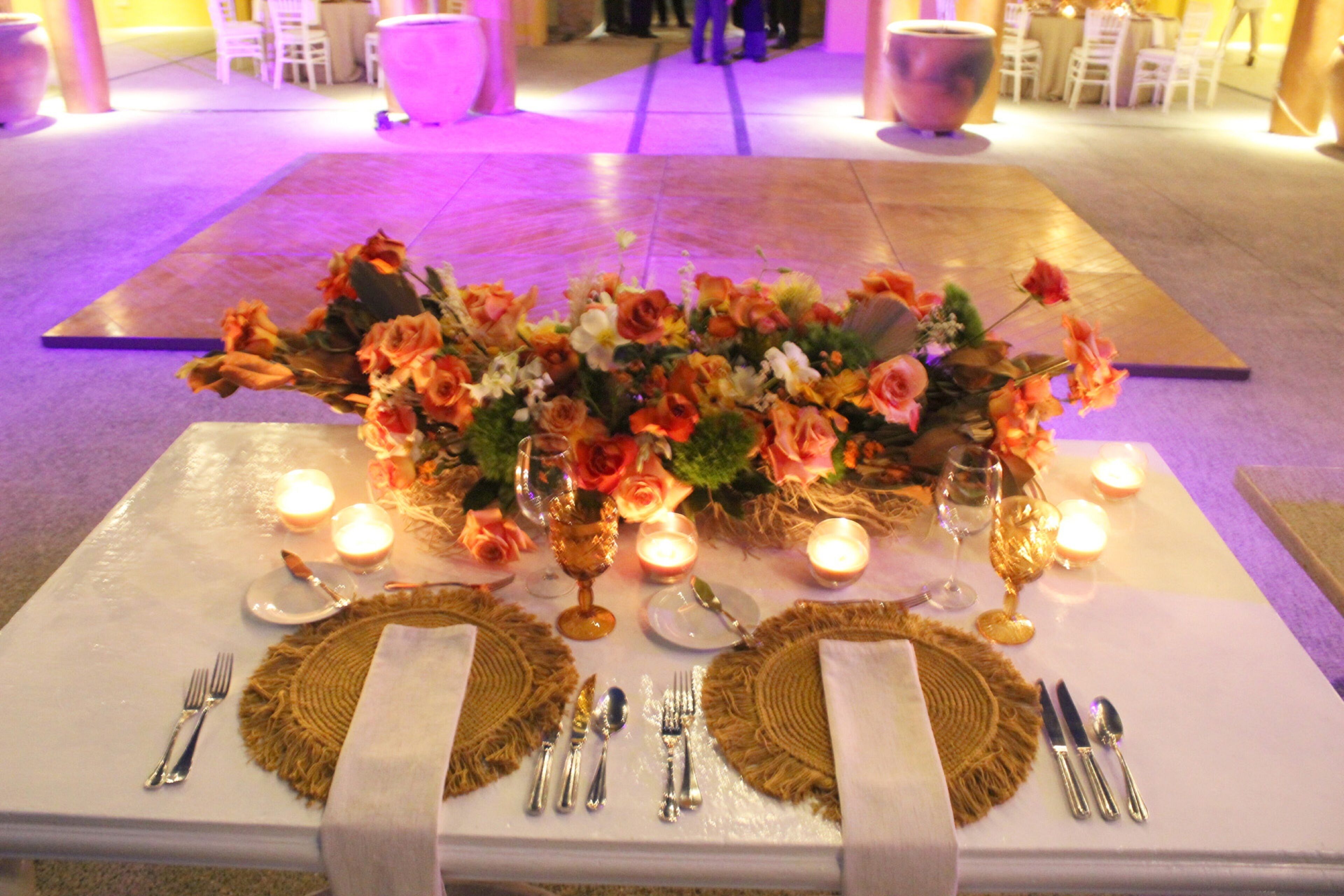 A table set for a meal with a centerpiece of flowers, candles, and silverware.