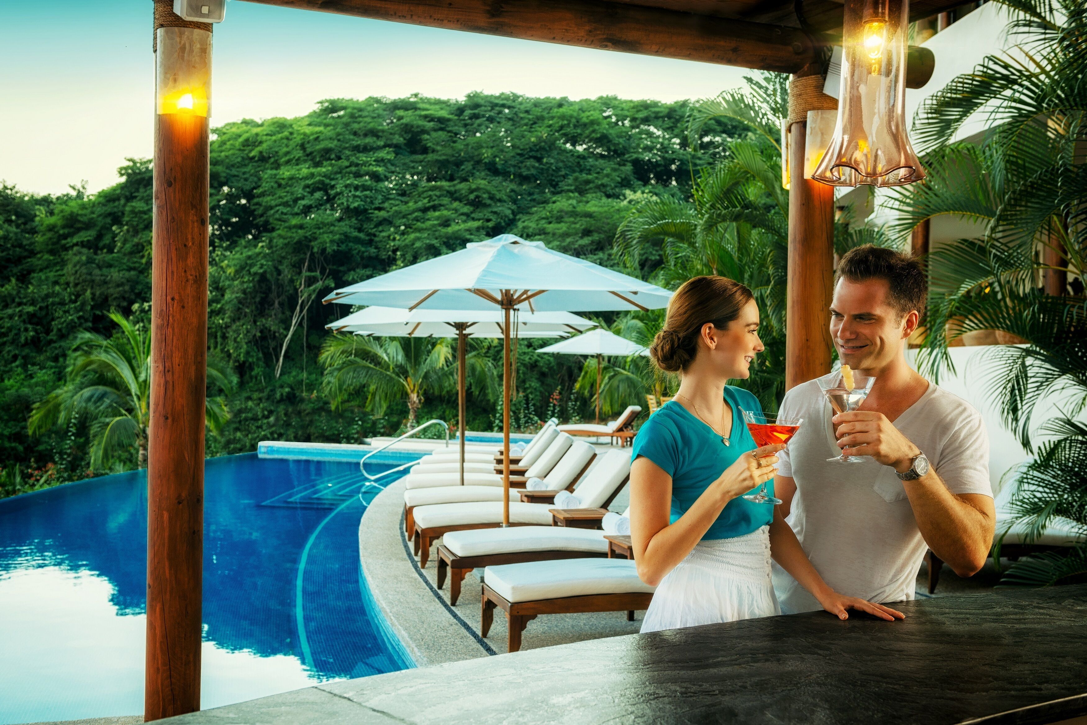 A poolside area with lounge chairs, umbrellas, and a bar.