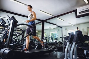 Uma academia com esteiras, aparelhos de musculação e um espelho grande na parede.