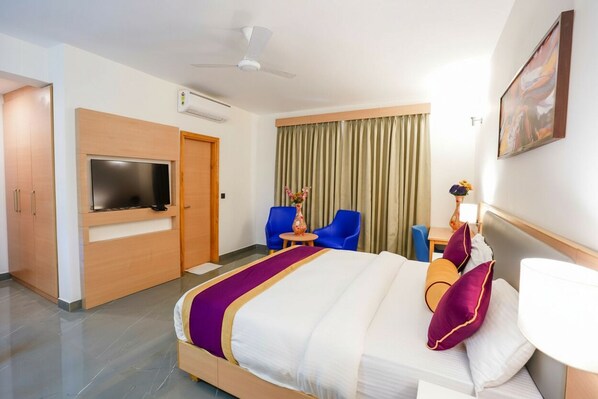 A hotel room with a bed, a TV, a desk, and a chair. - Hotel Meraden Opus (Anjuna)