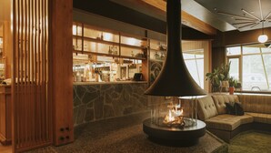 A cozy lobby with a stone wall, wooden paneling, a stone fireplace, and a seating area with a sofa and a potted plant. - Hotel Zed Tofino (Tofino)