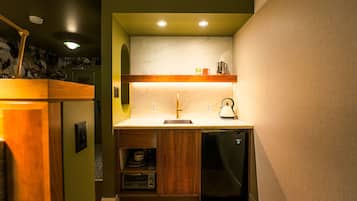 Una cocina compacta con un lavamanos, una tetera y un horno integrado.