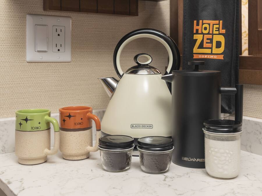 Un piano di lavoro in cucina con un bollitore, due tazze, una macchina per il caffè e barattoli di spezie.