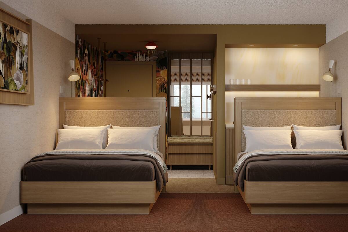 Une chambre d’hôtel avec deux lits, un petit coin salon et des œuvres d’art accrochées aux murs.