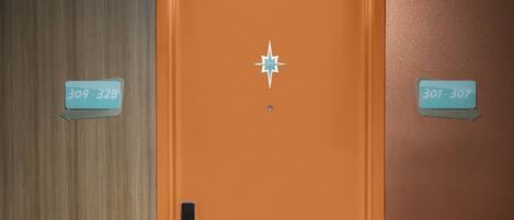 Puerta de una habitación de hotel con un adorno con forma de estrella y dos letreros que indican los números de las habitaciones 309-328 y 301-307.