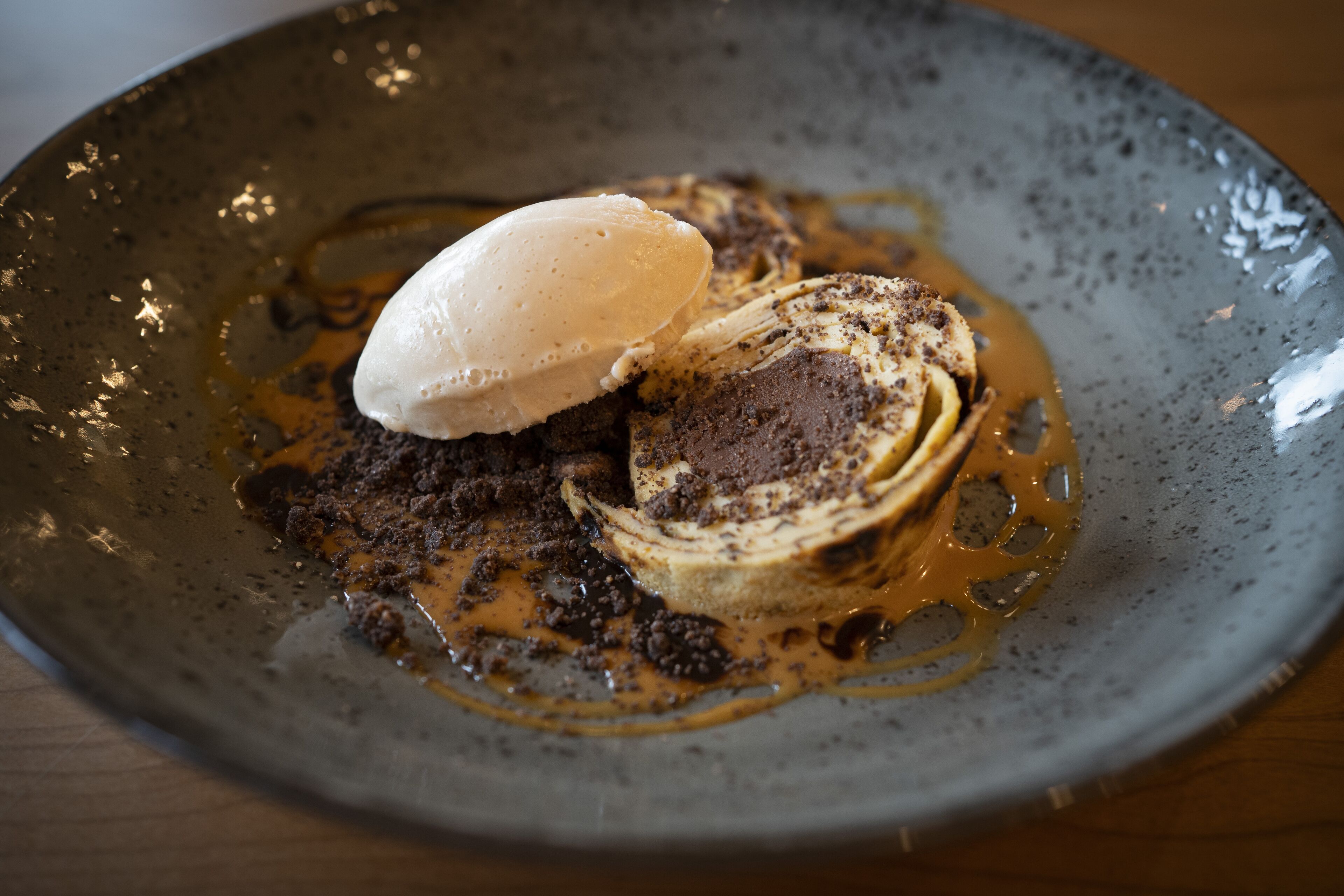 A dessert with a scoop of ice cream on a plate with chocolate cake and caramel sauce.