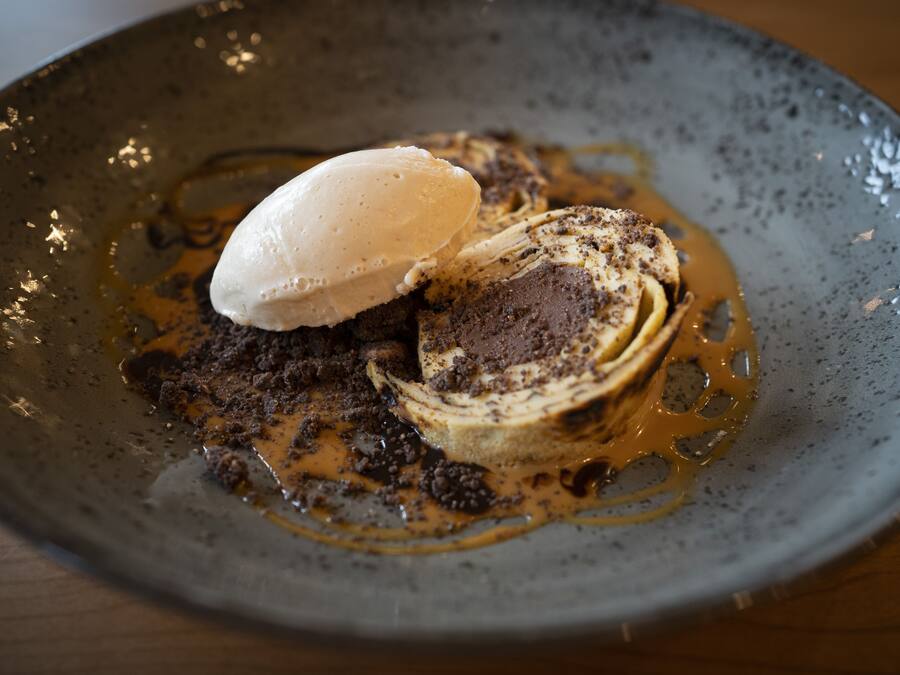 A dessert with a scoop of ice cream on a plate with chocolate cake and caramel sauce.