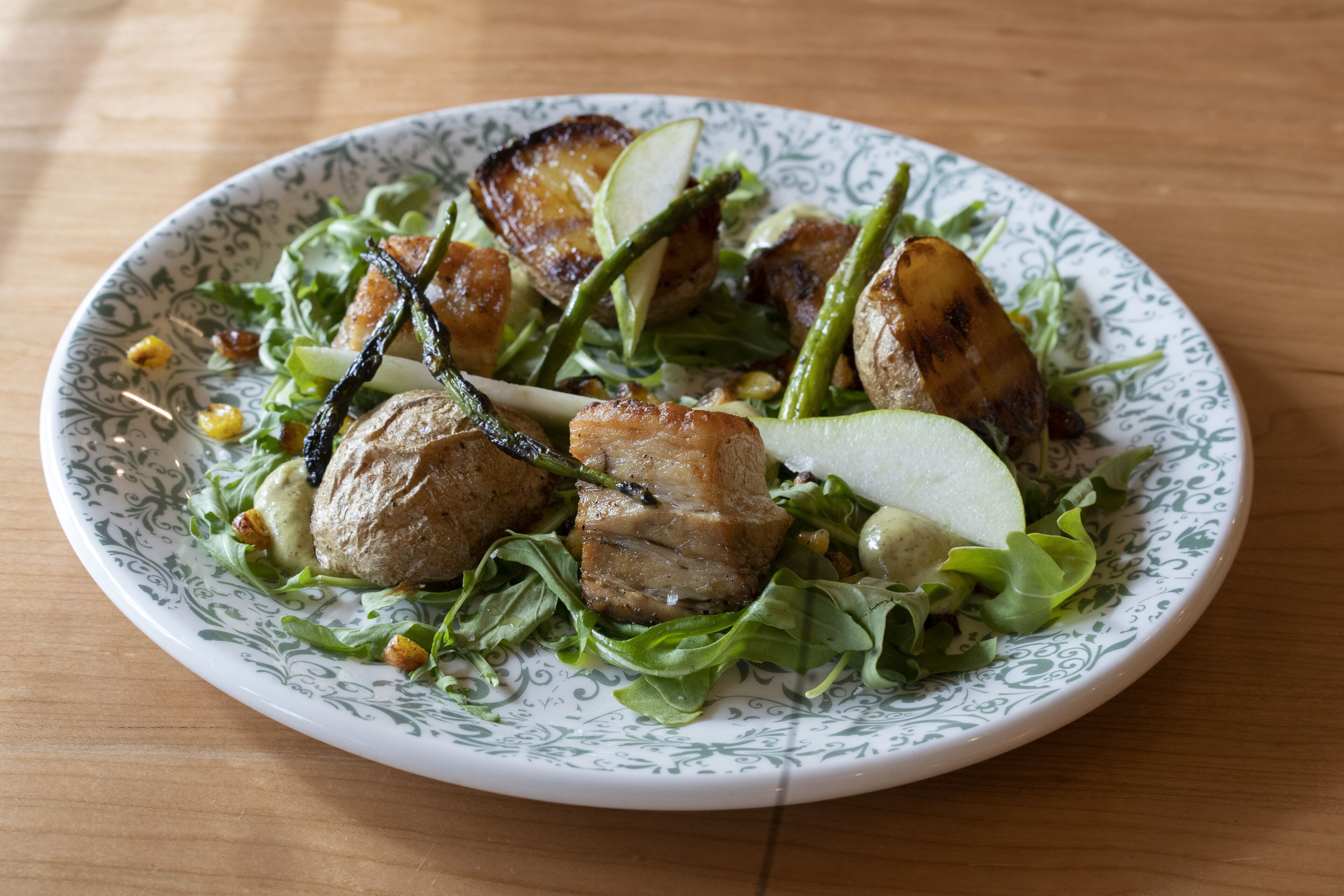 A plate of food with grilled meat, vegetables, and a decorative plate.