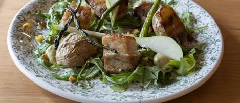 A plate of food with grilled meat, vegetables, and a decorative plate.