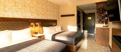 A hotel room with two beds, a TV, a minibar, and a patterned carpet.