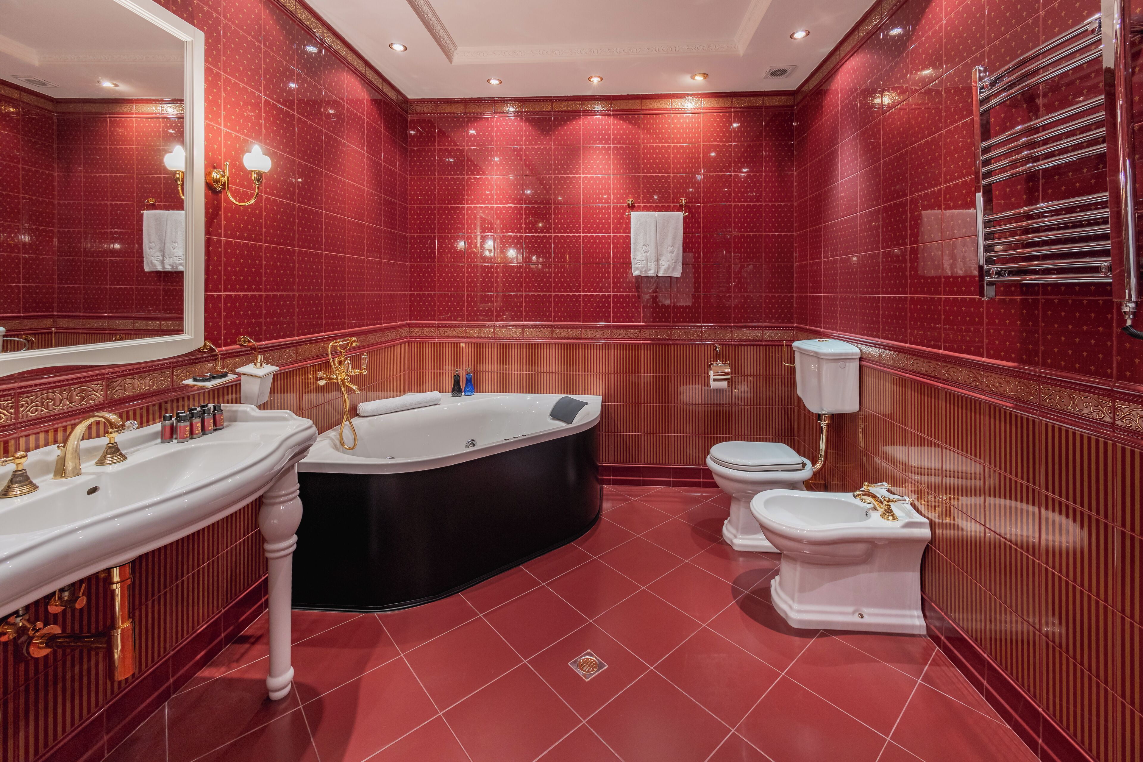 A luxurious bathroom with a large mirror, a bathtub, a toilet, and a sink.