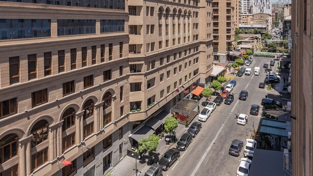 Een meerlaags hotel met een centrale binnenplaats, een overdekte doorgang en een parkeerplaats met meerdere auto's.