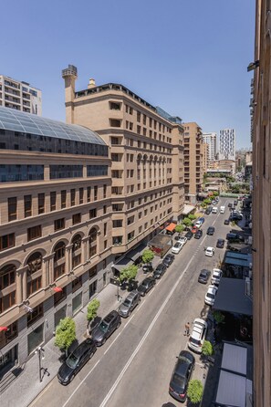 Un hotel de varios pisos con un patio central, un corredor cubierto y un estacionamiento con varios automóviles.