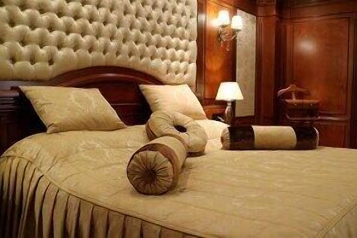 A bed with a tufted headboard, a lamp, and a bedside table.