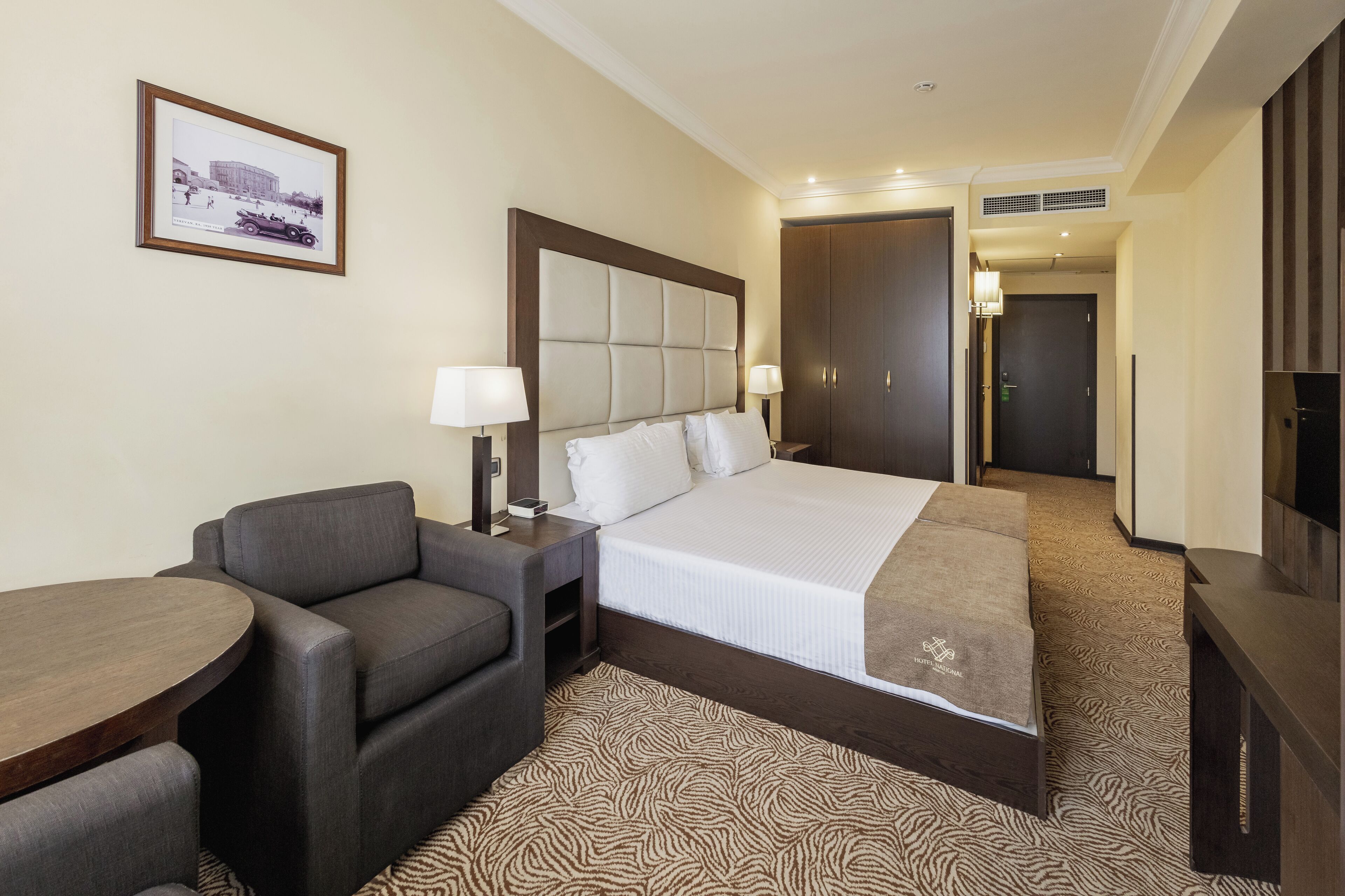 Una habitación de hotel con una cama grande, un sofá, una mesita y un televisor.