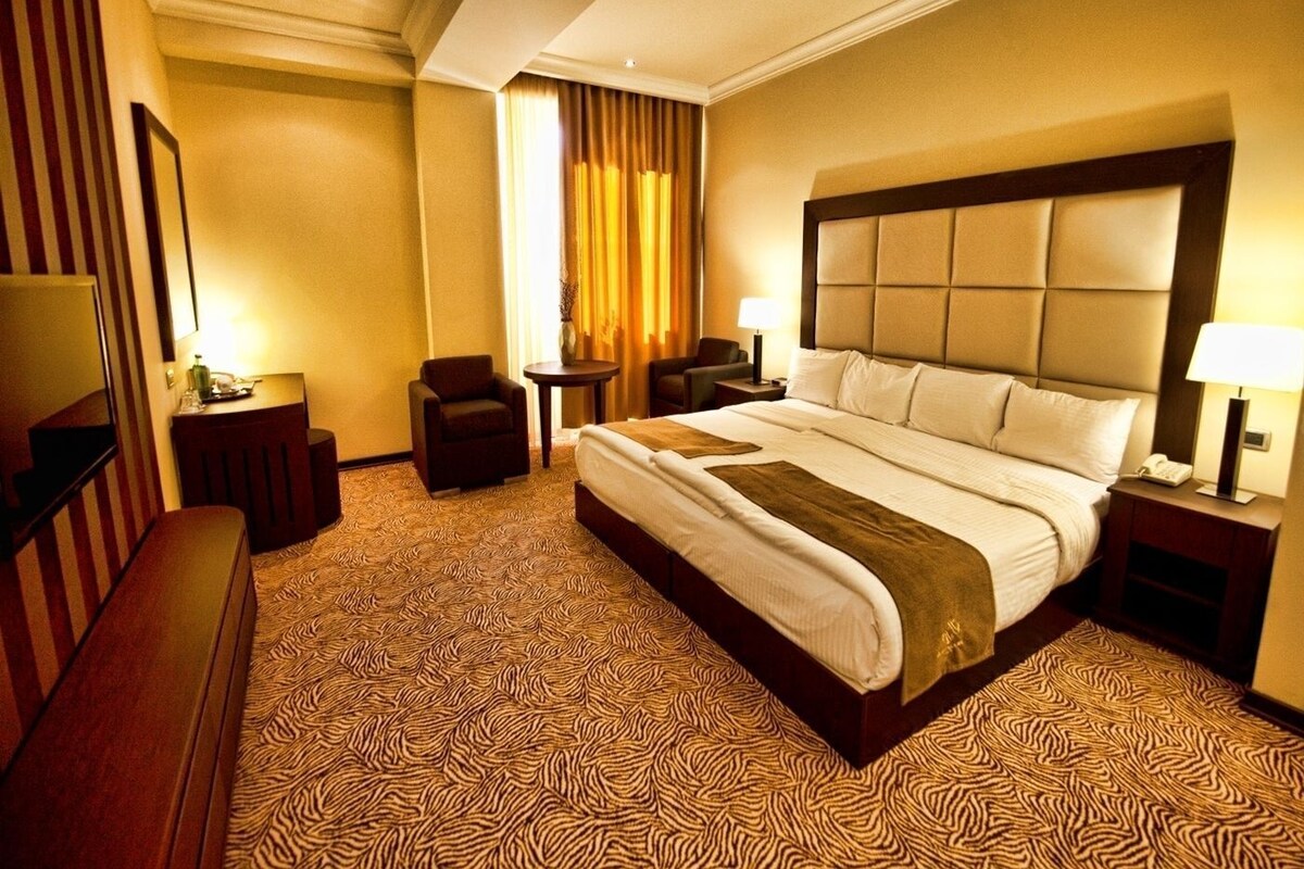 Una habitación de hotel con una cama grande, un escritorio, una silla y un televisor.