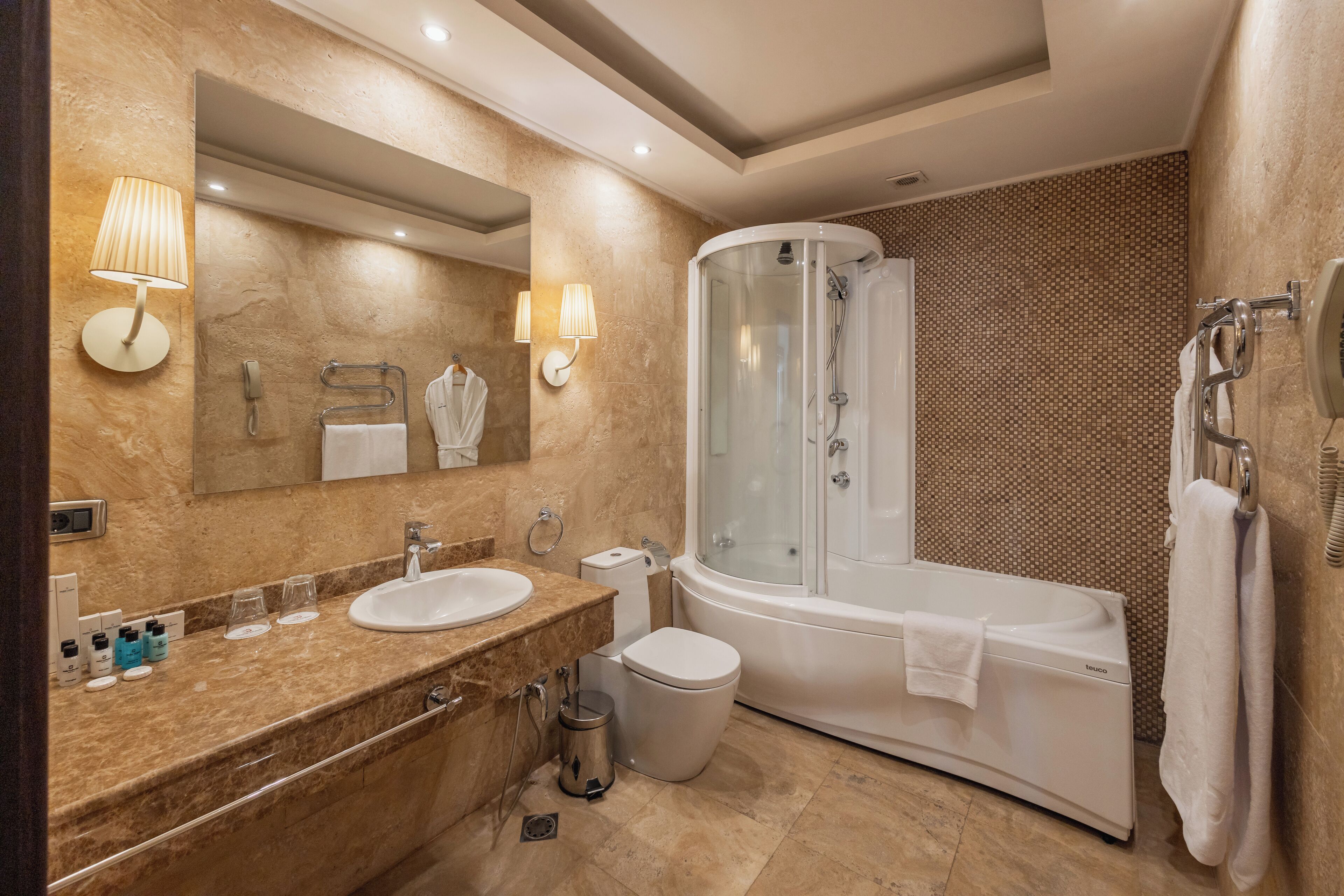 Un baño moderno con dos lavamanos, una ducha con mampara de vidrio, un inodoro y un espejo grande.