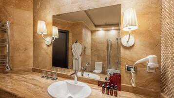 Un baño moderno con encimera de mármol, un espejo grande, un lavabo, una ducha y un secador de pelo fijado en la pared.