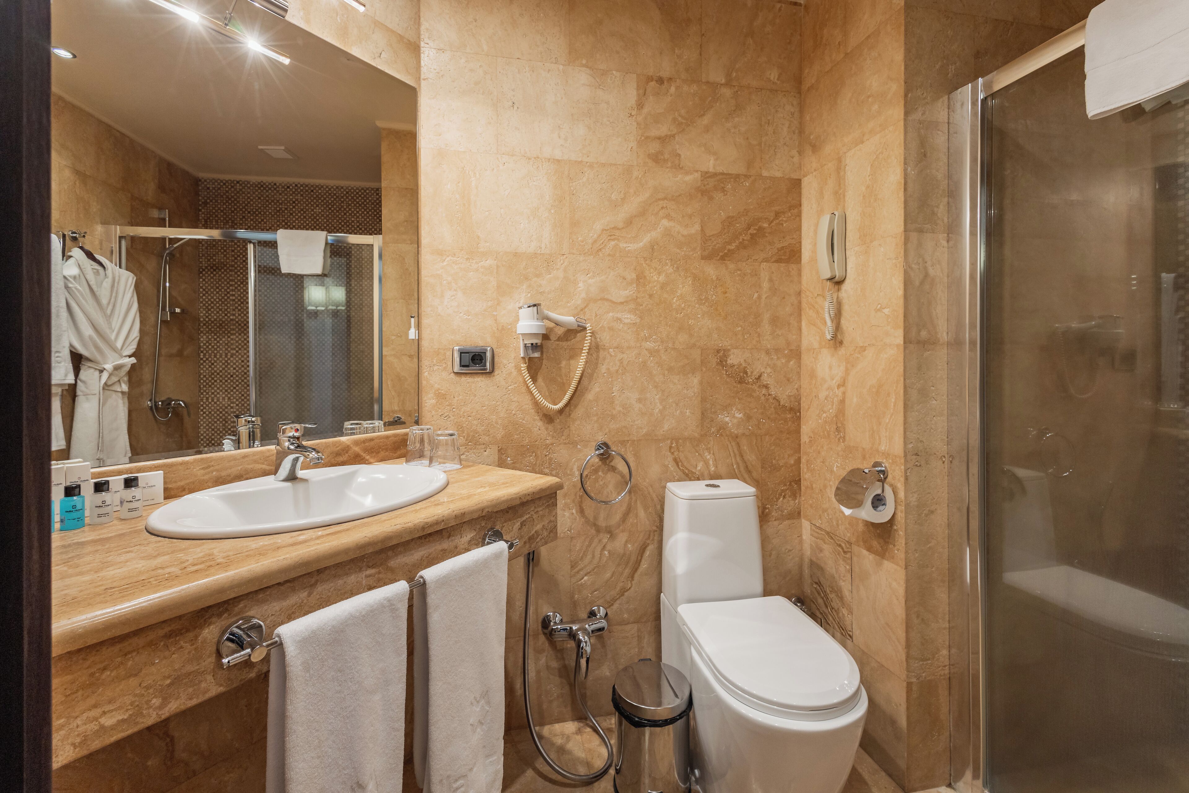 Une salle de bain moderne avec un lavabo en marbre, une douche à parois de verre et des toilettes.