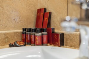 Een badkamermeubel met rode en zwarte flesjes, waarschijnlijk toiletartikelen, en enkele rode dozen.