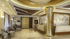 A hotel lobby with a reception desk, seating area, and a decorative chandelier. - National by Stellar Hotels, Yerevan (Yerevan)