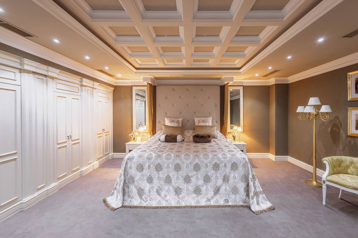 Ein Schlafzimmer mit einem großen Bett, einem Nachttisch, einer Lampe und einem Sessel.